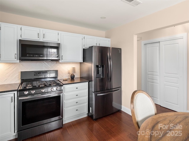 kitchen with white cabinetry, stainless steel appliances, dark wood-type flooring, and backsplash