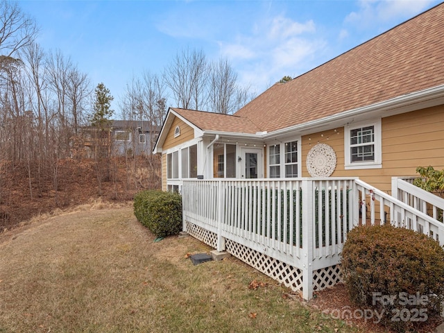 view of side of home featuring a wooden deck, a lawn, and a sunroom