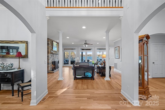 foyer entrance with crown molding, decorative columns, and light hardwood / wood-style floors