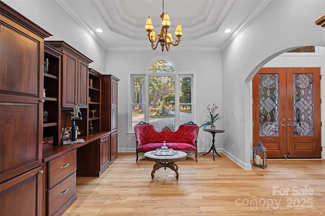 sitting room featuring light hardwood / wood-style flooring, a tray ceiling, crown molding, an inviting chandelier, and french doors