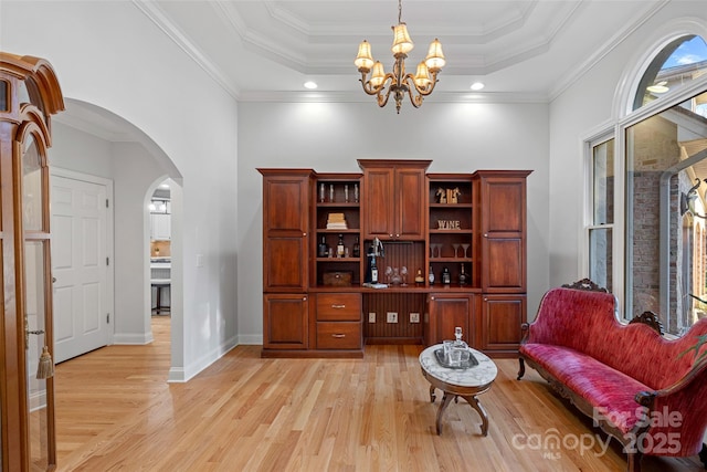 sitting room with a raised ceiling, ornamental molding, and a chandelier