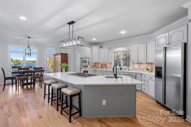 kitchen featuring sink, pendant lighting, stainless steel appliances, a kitchen island with sink, and backsplash