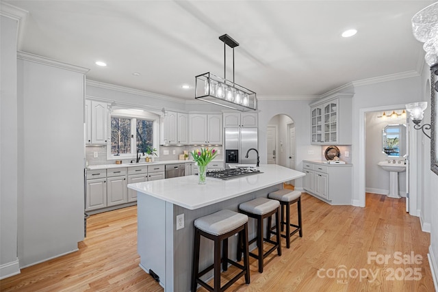 kitchen with a kitchen island, appliances with stainless steel finishes, tasteful backsplash, a kitchen bar, and light hardwood / wood-style floors