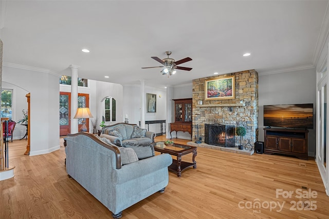 living room featuring a fireplace, light hardwood / wood-style flooring, ornamental molding, and ornate columns