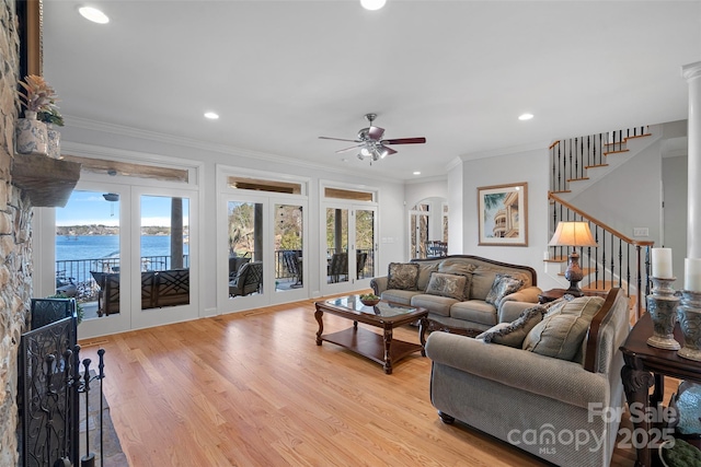 living room featuring light hardwood / wood-style flooring, ornamental molding, ceiling fan, and a water view