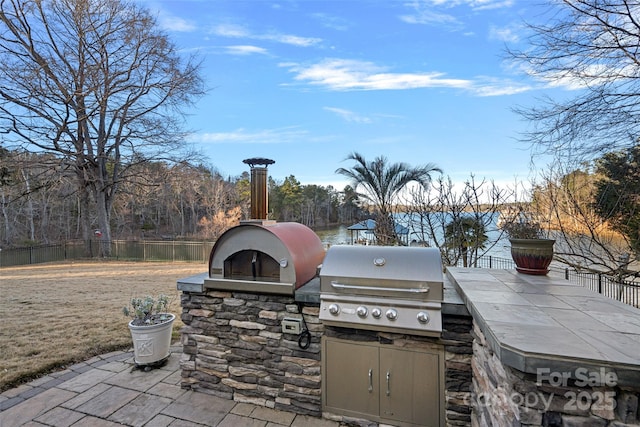 view of patio with area for grilling, grilling area, and a water view