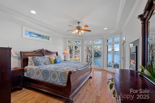 bedroom featuring a water view, crown molding, light hardwood / wood-style flooring, access to outside, and ceiling fan