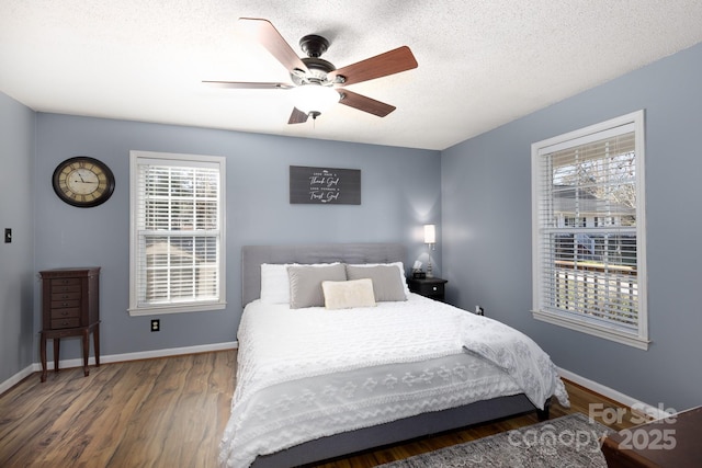 bedroom with a ceiling fan, a textured ceiling, baseboards, and wood finished floors