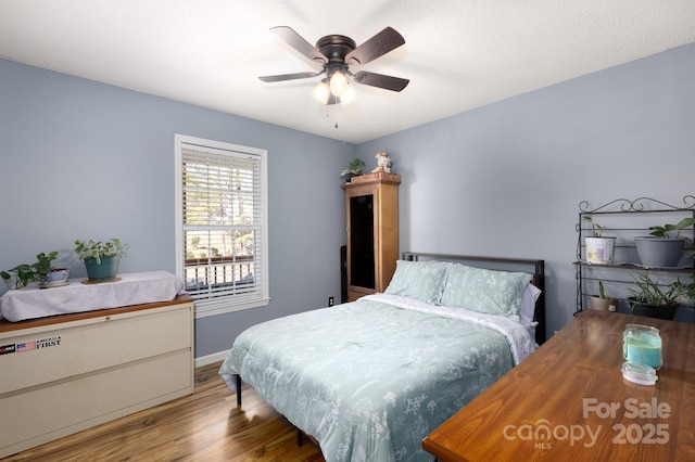 bedroom featuring wood finished floors, a ceiling fan, and baseboards