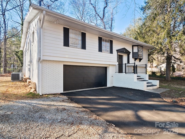 bi-level home featuring a garage and central air condition unit