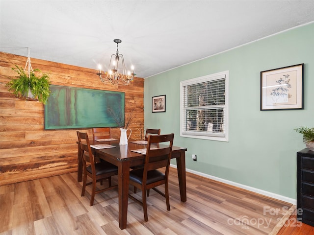 dining space with an inviting chandelier, wood-type flooring, and wood walls