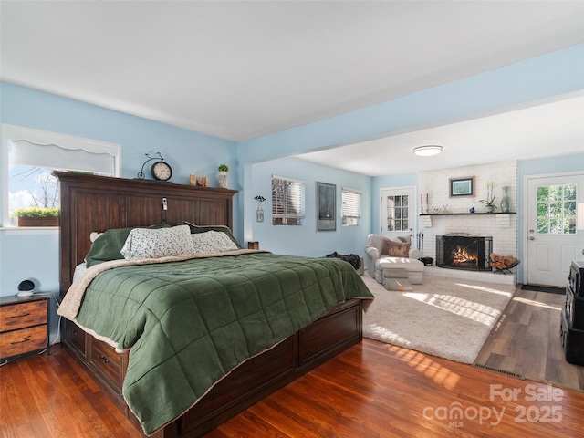 bedroom featuring dark hardwood / wood-style flooring and a brick fireplace