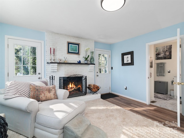 living room featuring dark wood-type flooring and a brick fireplace