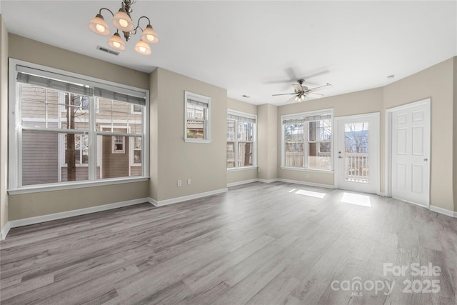 unfurnished living room with ceiling fan with notable chandelier and light hardwood / wood-style floors