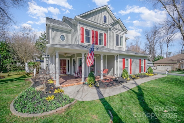 traditional-style home featuring a garage, covered porch, fence, and a front lawn