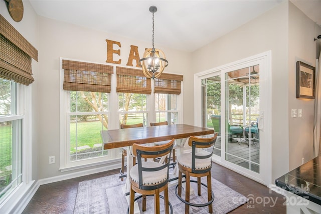 dining space featuring plenty of natural light, dark wood-style flooring, a notable chandelier, and baseboards