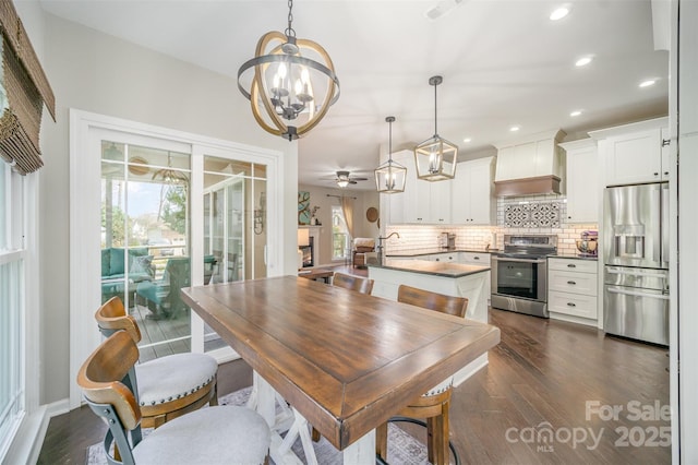 dining room with dark wood finished floors, a fireplace, recessed lighting, visible vents, and ceiling fan with notable chandelier