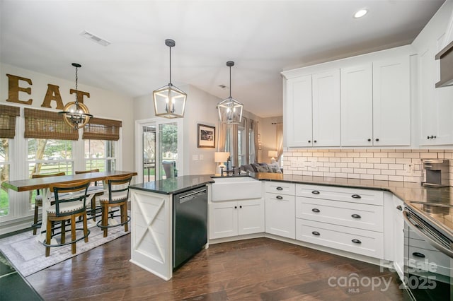 kitchen with a peninsula, black appliances, dark wood-style floors, and a sink