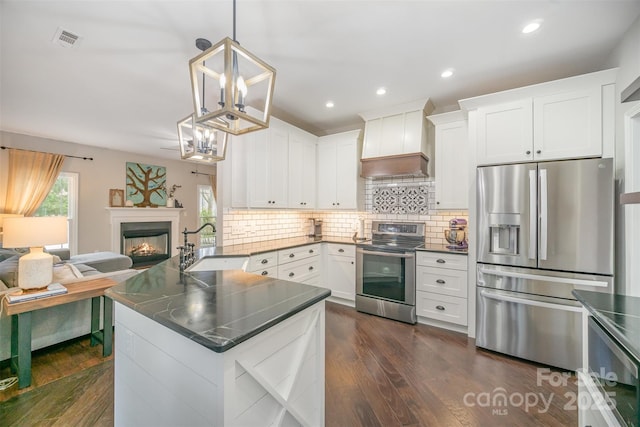 kitchen featuring open floor plan, a peninsula, custom exhaust hood, stainless steel appliances, and a sink