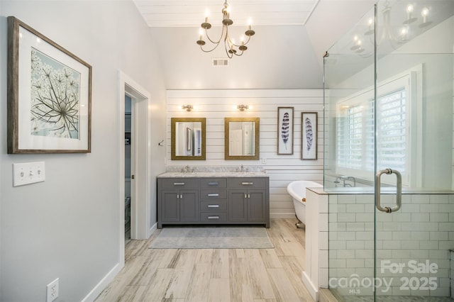 bathroom featuring wood finished floors, a sink, visible vents, a freestanding bath, and a shower stall