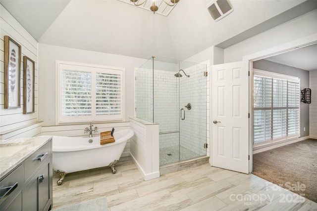 bathroom featuring a stall shower, visible vents, vaulted ceiling, vanity, and a freestanding tub