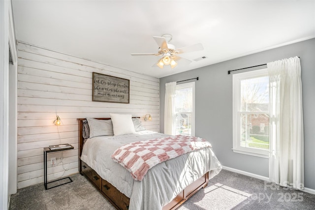 bedroom with carpet floors, multiple windows, wood walls, and visible vents