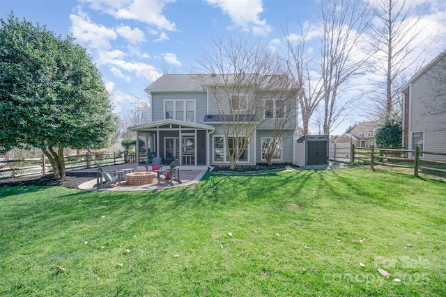 rear view of property with a sunroom, an outdoor fire pit, a yard, and a shed