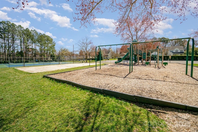 community playground featuring a tennis court, fence, and a lawn