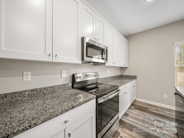 kitchen featuring white cabinetry, dark hardwood / wood-style flooring, stainless steel appliances, and dark stone countertops