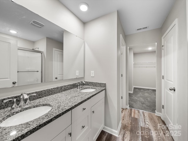 bathroom with walk in shower, vanity, and hardwood / wood-style flooring