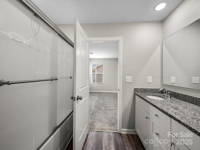 bathroom featuring hardwood / wood-style flooring, vanity, and bath / shower combo with glass door