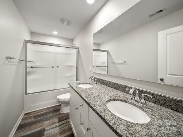 full bathroom with bath / shower combo with glass door, wood-type flooring, vanity, and toilet