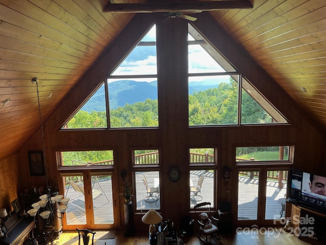 living room with a mountain view, wood ceiling, high vaulted ceiling, and wood walls