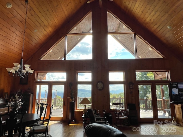 living room featuring a healthy amount of sunlight, beam ceiling, wooden walls, and wood-type flooring