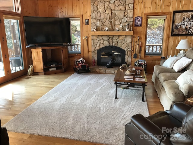 living room featuring wooden walls, a fireplace, and light wood-type flooring