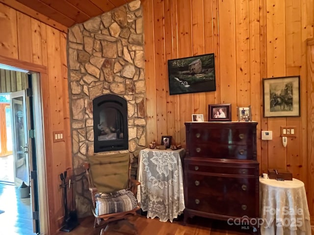 living area featuring vaulted ceiling, a fireplace, and wooden walls