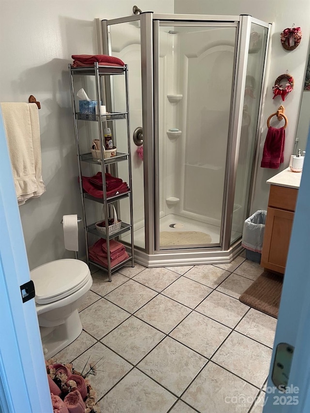 bathroom featuring tile patterned flooring, an enclosed shower, vanity, and toilet