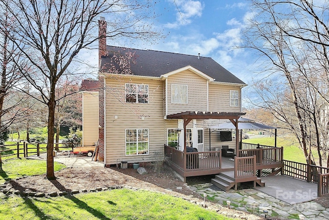 rear view of house with a wooden deck, a pergola, and a lawn