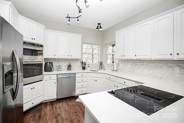 kitchen with sink, stainless steel appliances, white cabinets, dark hardwood / wood-style flooring, and decorative backsplash