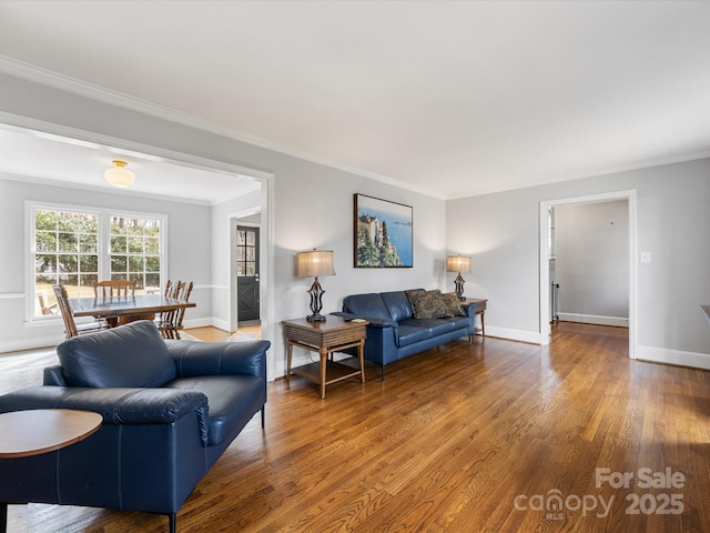 living room featuring baseboards, ornamental molding, and wood finished floors