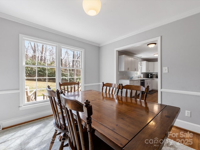 dining space with baseboards, crown molding, and wood finished floors