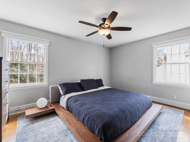 bedroom with ceiling fan, wood finished floors, and baseboards