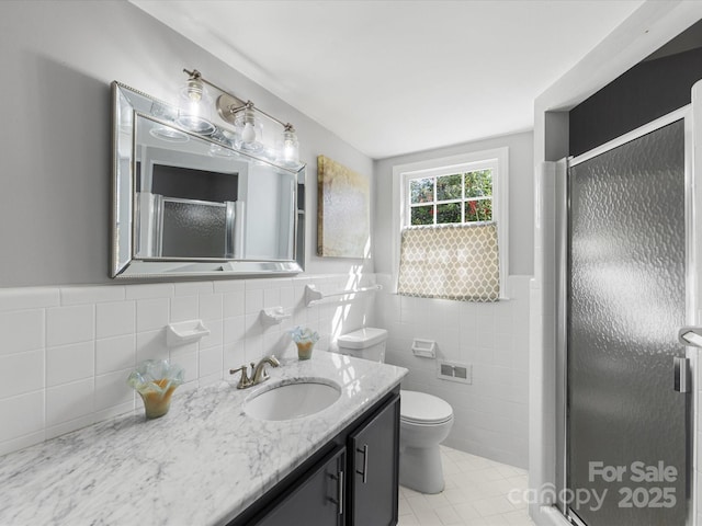 full bath featuring wainscoting, toilet, a shower with door, vanity, and tile walls