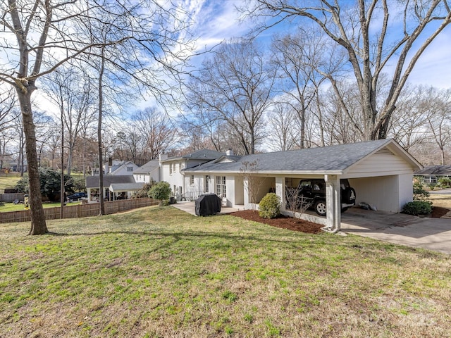 view of front of home featuring driveway, a front lawn, fence, and an attached carport