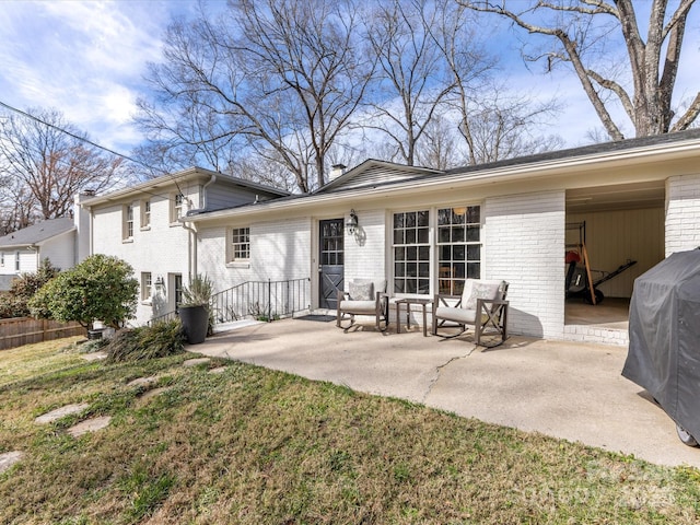 rear view of house featuring a yard, brick siding, and a patio area