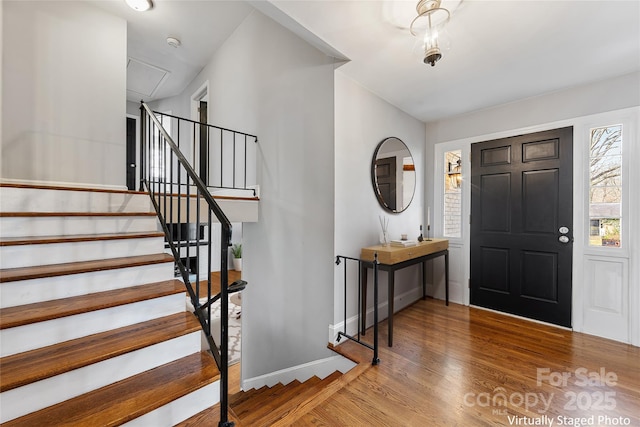 foyer with stairway, baseboards, and wood finished floors