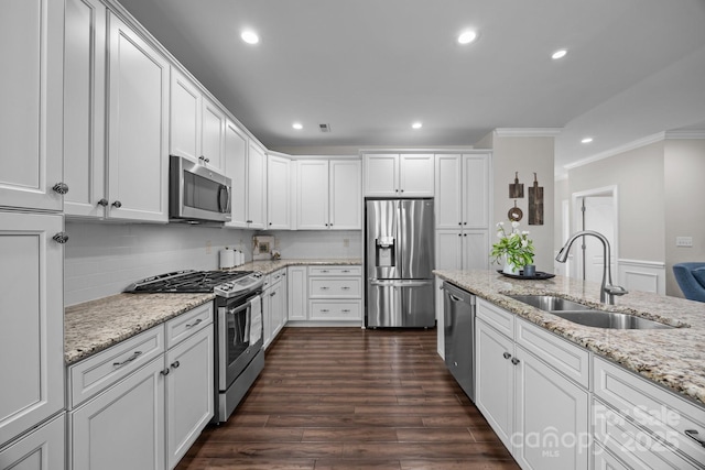 kitchen featuring stainless steel appliances, a sink, white cabinetry, light stone countertops, and crown molding