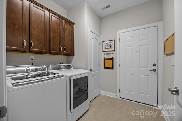 clothes washing area featuring light tile patterned floors, visible vents, baseboards, cabinet space, and washing machine and clothes dryer