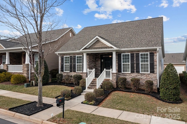 view of front of property featuring stone siding, a front lawn, and roof with shingles