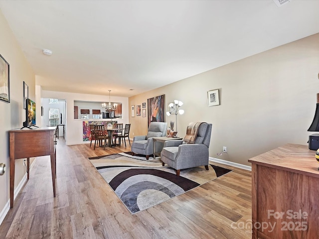 living room with an inviting chandelier and light hardwood / wood-style flooring